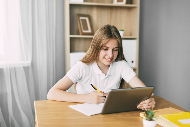 Girl writing in front of laptop